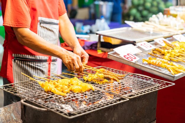 The man grilled squid and flip on chracoal grill at street food market