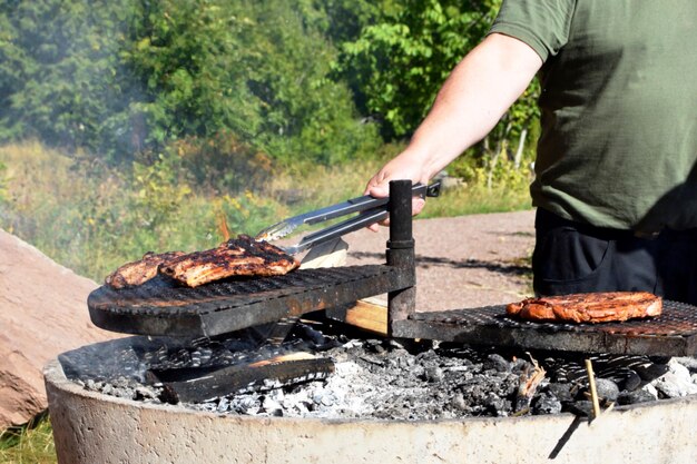 Мужчина жарит мясо на гриле