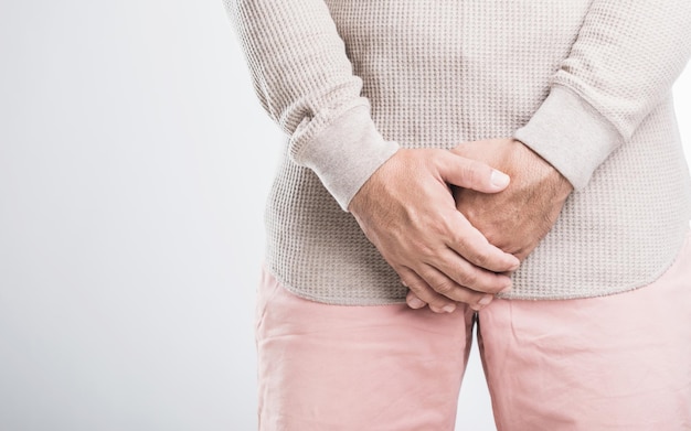 a man grimaces in pain holding his groin area with both hands symbolizing discomfort from a health issue like gonorrhea the image highlights mens health and the importance of addressing symptoms