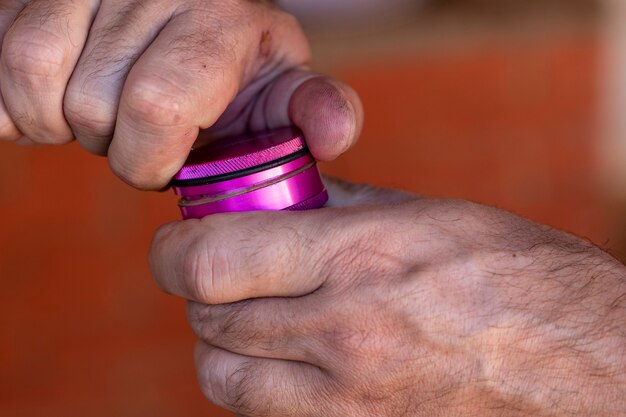 Uomo che macina marijuana per fare una canna.