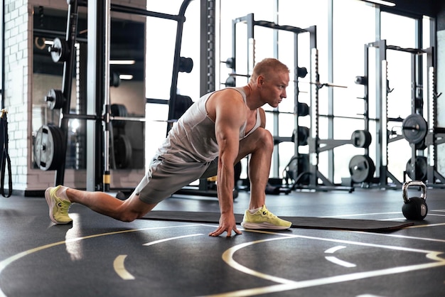 Uomo in palestra che fa esercizi di stretching sul pavimento