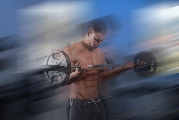 Photo man in the gym exercising biceps with barbell