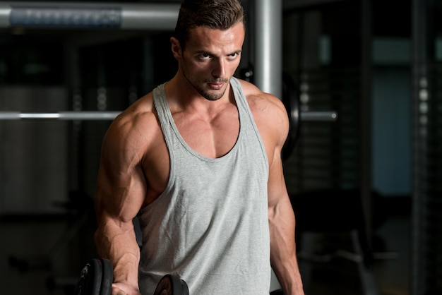 Man In The Gym Exercising Biceps With Dumbbells