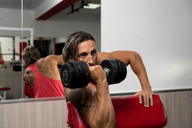 Man In The Gym Exercising Biceps With Dumbbells