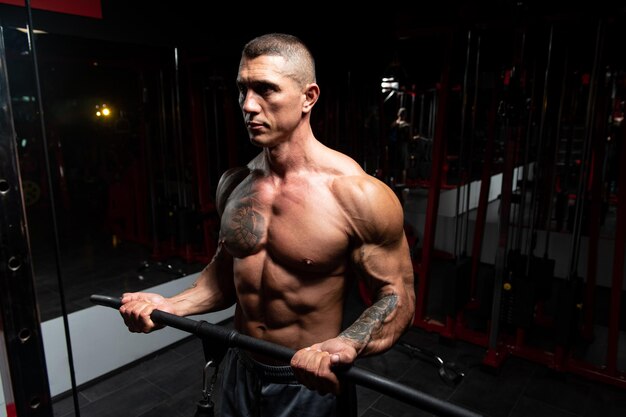 Man In The Gym Exercising On His Biceps On Machine With Cable In The Gym