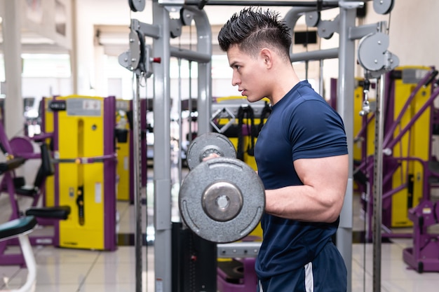 Photo man in gym lifting weights with strong training