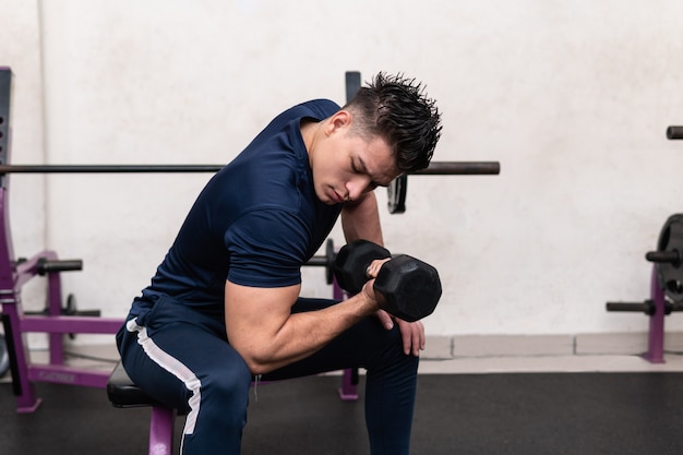 Man in gym lifting weights with strong training