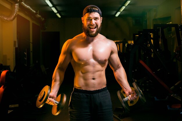 Man in gym training with dumbbells