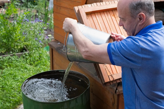 Man haalt water uit de put om bloemen in de tuin water te geven