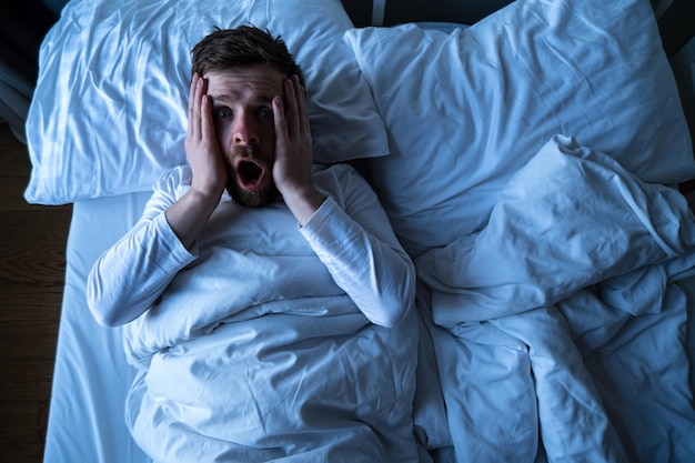 Man had a terrible nightmare he woke up in horror looking frightened with big eyes at the camera