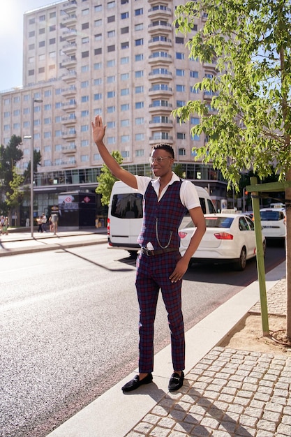 Мужчина окликает таксиста, поднимая руку, чтобы подать сигнал такси в городе