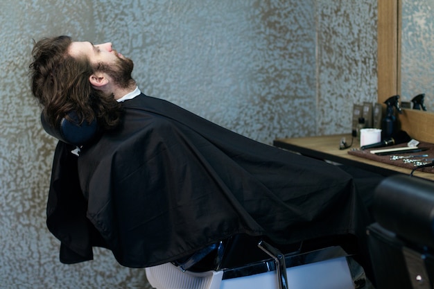 Man at the hairdressing salon sitting in the armchair, waiting for a barber