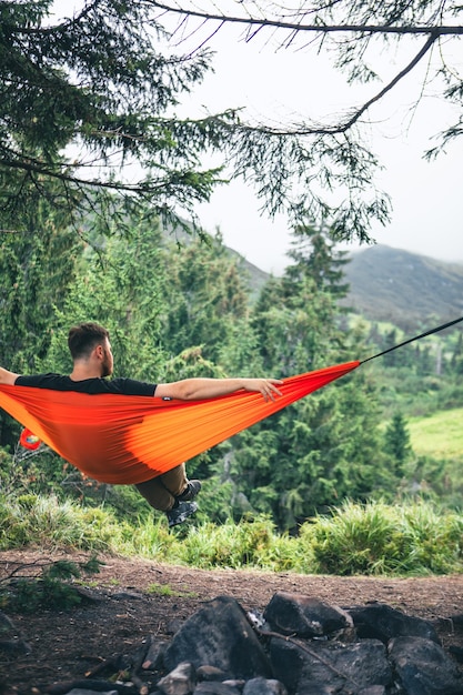 man in hammock at camping site mountains on background copy space