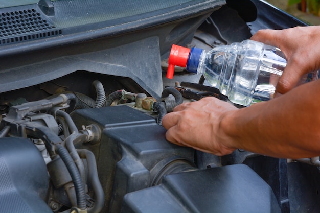 Foto man mano su aggiungere la batteria dell'acqua distillata prima di guidare la macchina.