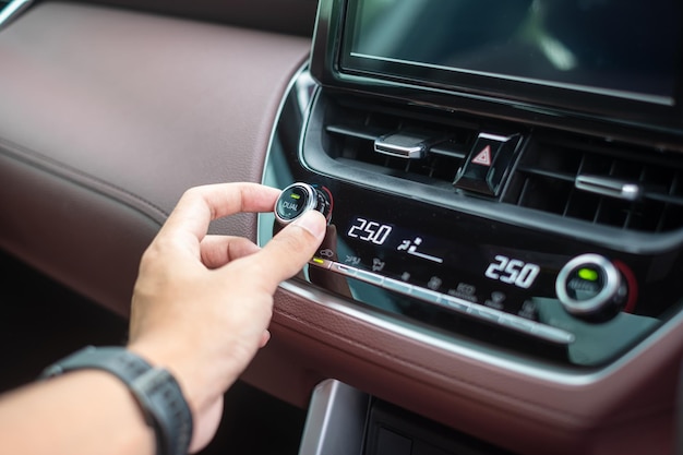 Man hand adjusting temperature the air flowing during driving car on the road air conditioner cooling system inside the car Adjust temperature and transport concept