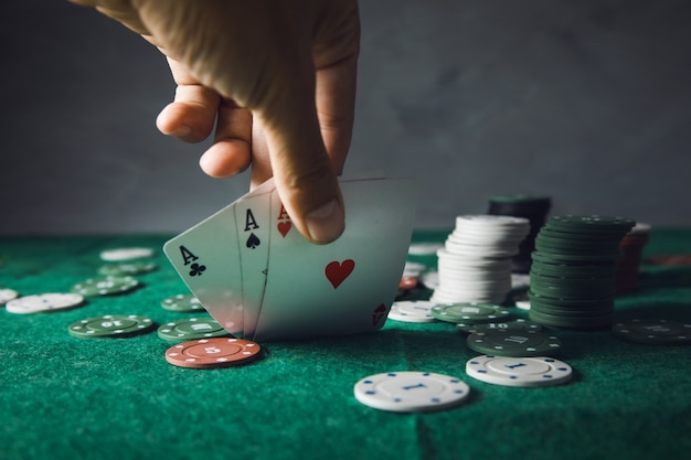 Carte di mano dell'uomo che giocano a poker sul tavolo verde