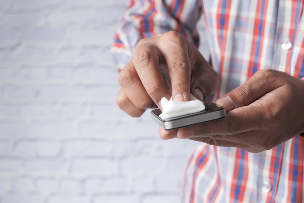 Man hand cleaning mobile phone display for preventing virus