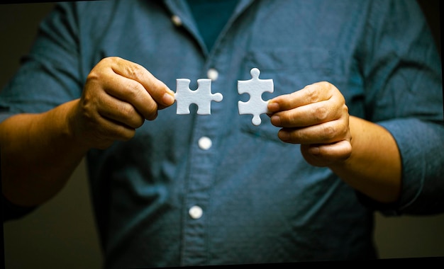 Man hand connecting jigsaw puzzle Business solutions and success concept strategy and teamwork