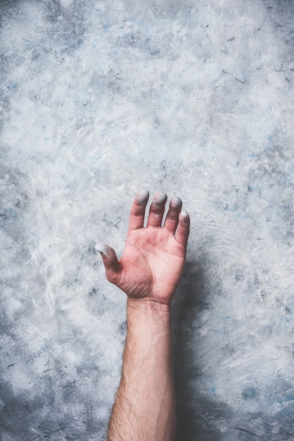 Photo man hand covered with paint on gray concrete wall background