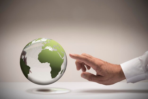 Man hand and finger pointing a glass globe, concept image for choosing a trip destination.