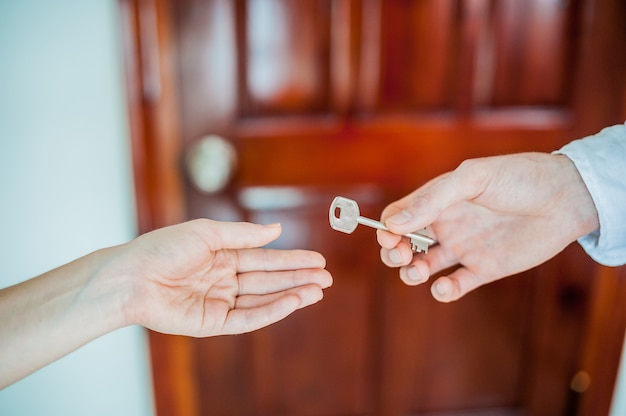 Man hand geeft een zeer belangrijk wijfje op achtergrond van houten deur. Behandel het concept van onroerend goed