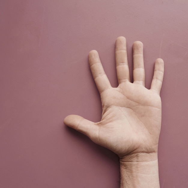 man hand gesturing on the pink wall