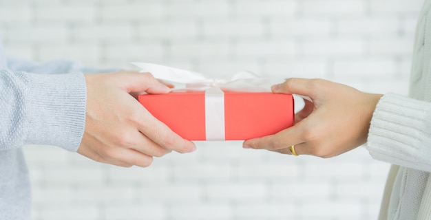 man hand giving red gift box to woman