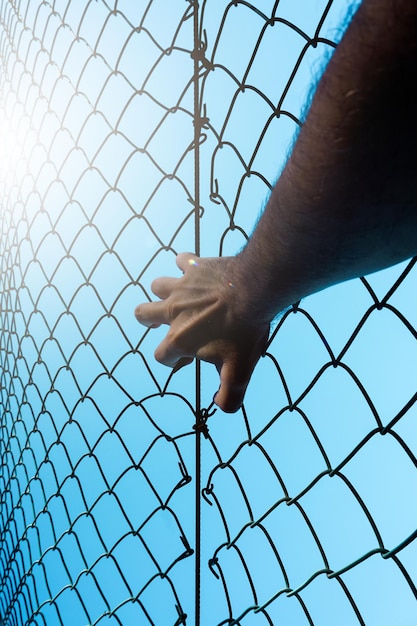 man hand grabbing metallic fence, feeling free