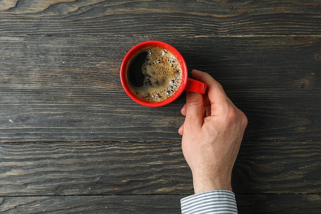 Photo man hand hold cup of coffee with frothy foam on wooden