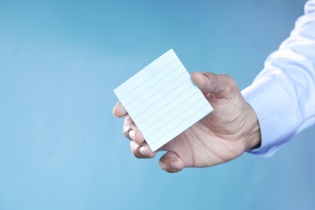 Man hand hold a sticky note against blue background