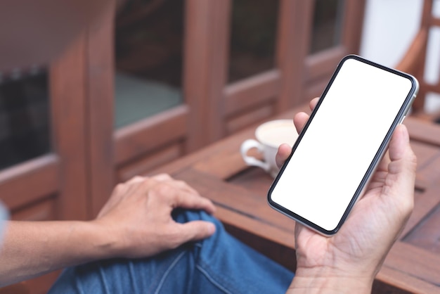 Man hand holding blank screen mobile phone at coffee shop