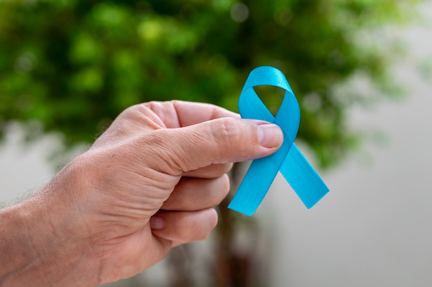 Man hand holding blue ribbon. Blue november. Prostate Cancer Prevention Month. Men's health.