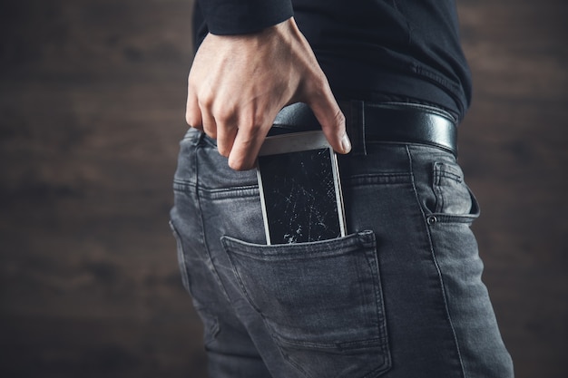 Photo man hand holding broken phone in pocket