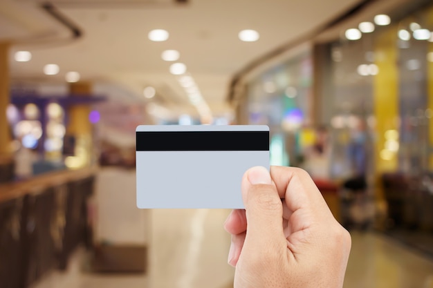 Man hand holding credit card on blur of shopping mall 