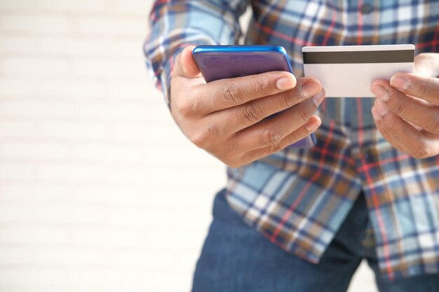 Man hand holding credit card and using smart phone shopping online