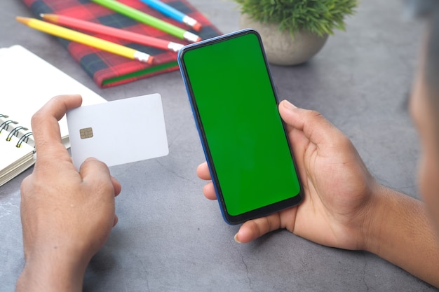 Человек рука кредитной карты и с помощью смарт-телефона покупки в Интернете