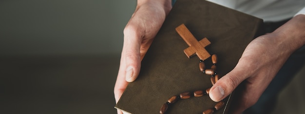 Photo man hand holding cross on bible book