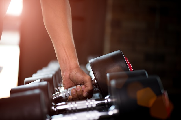 Man hand holding dumbbell in the gym bodybuilding. exercise and healthy lifestyle concept.