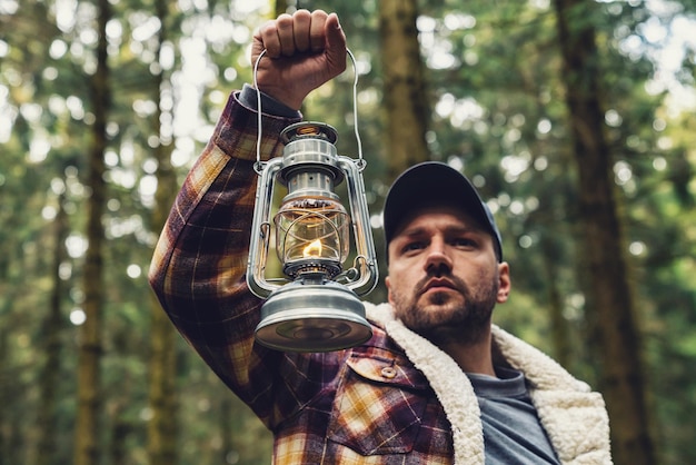 Man hand holding gas lantern in the deep forest