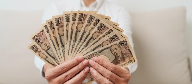 Man hand holding Japanese Yen banknote stack Thousand Yen money Japan cash Tax Recession Economy Inflation Investment finance and shopping payment concepts