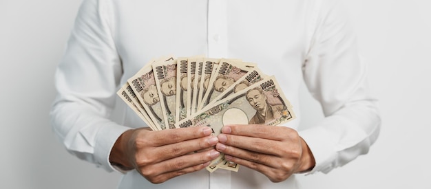 Man hand holding Japanese Yen banknote stack Thousand Yen money Japan cash Tax Recession Economy Inflation Investment finance and shopping payment concepts