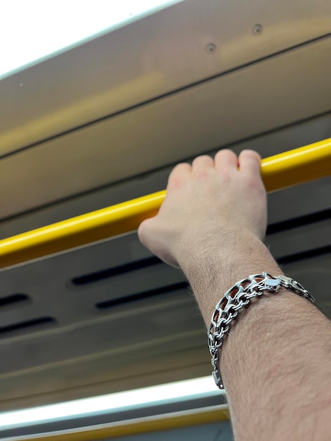 Man hand holding onto the handgrip of the bus Hand of person holding on to the handle of public transport