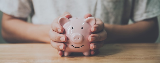 Man hand holding piggy bank on wood table