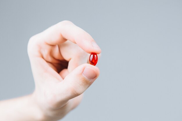 Man hand holding red pill isolated