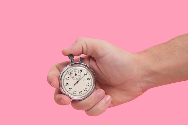 Man hand holding stopwatch on pink background.