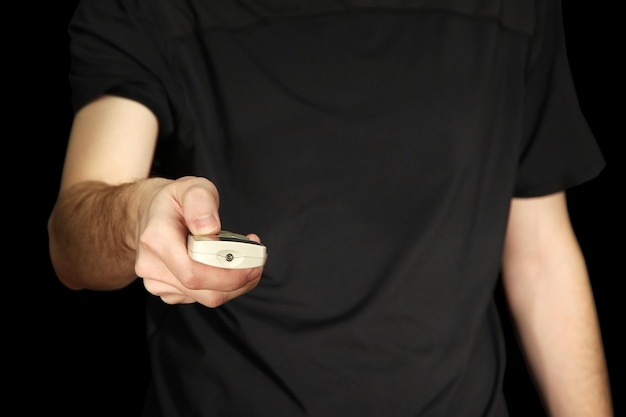 Man hand holding a TV remote control on dark background