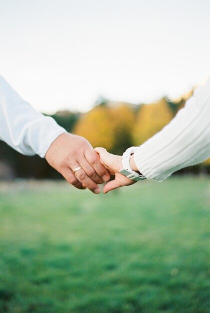 Man hand holds woman hand on a background of green grass