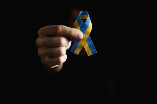 Man hand holds yellow blue ribbon