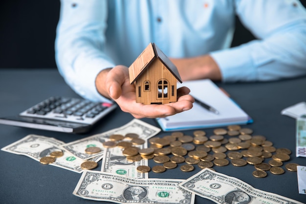 Man hand house model and money