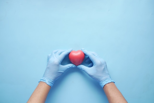 man hand in beschermende handschoenen met rood hart op blauw